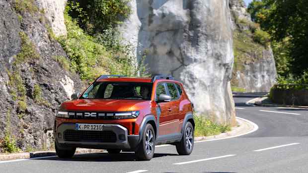 Frontansicht eines Dacia Duster LPG in Fahrt auf einer Straße mit felsiger Umgebung.