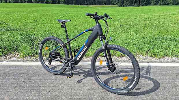 Seitliche Gesamtansicht des Grundig E275 E-Bikes vor einer Wiese.