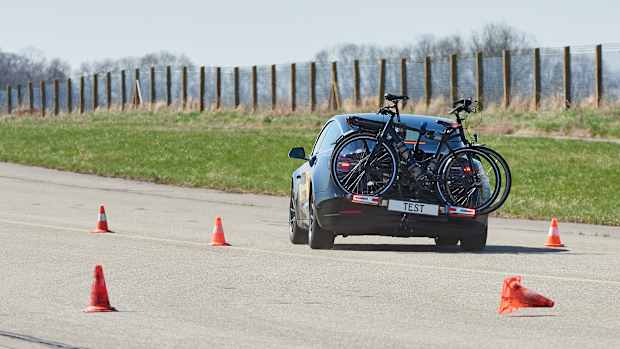 Ein Auto fährt mit einem befestigten Fahrradheckträger mit Fahrrädern einen Ausweichtest