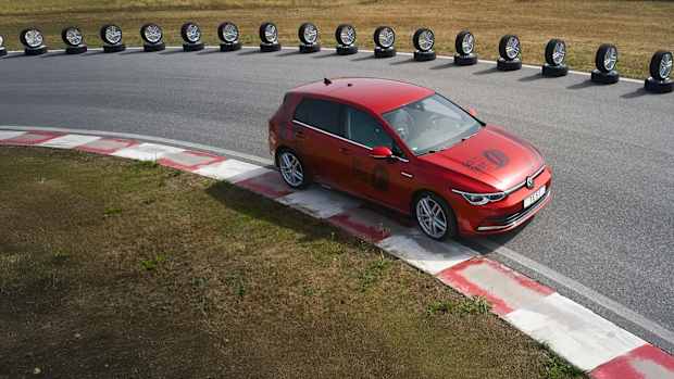Ein VW Golf fährt neben einer aufgereihten Reihe von Reifen