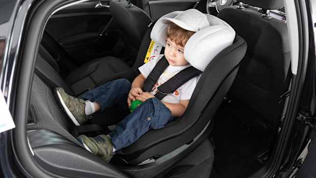 Ein Kind sitzt in einem Kindersitzt auf der Rückbank eines Autos