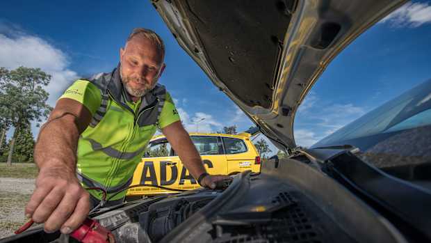 Ein ADAC Straßenwachtfahrer überbrückt eine Autobatterie