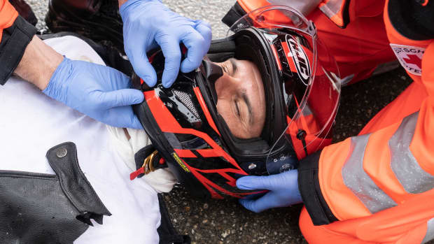Einem Mann wir nach einem Unfall der Helm vorsichtig abgenommen