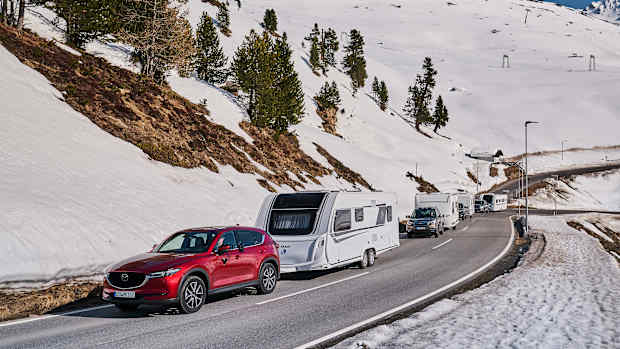 Autos mit Wohnwagen fahren durch eine Winterlandschaft