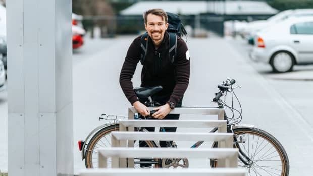 Ein Mann sperrt sein Fahrrad an einem Metall-Fahrradständer ab