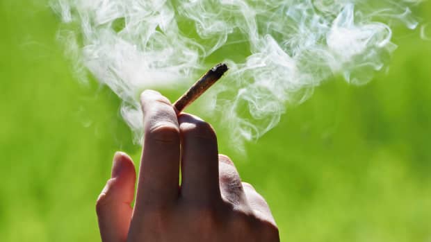 Ein qualmender Joint wird von jemandem gehalten