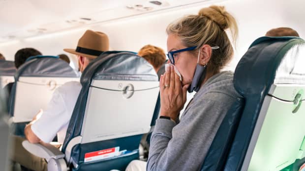 Eine Frau putzt sich im Flugzeug die Nase.