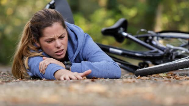 Eine junge Frau liegt am Boden nachdem sie vom Fahrrad gestürzt ist