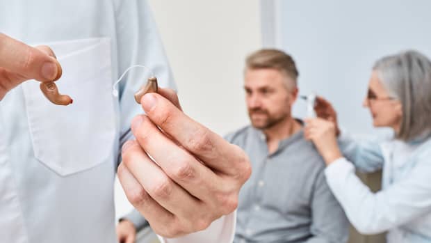 Audioprosthetis wählt nach der Höruntersuchung für hörgeschädigte Patienten zwischen Im-Ohr- und Hinter-dem-Ohr-Hörgeräten zur Behandlung von Taubheit