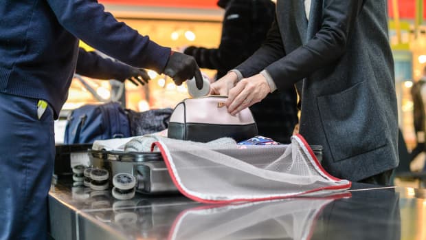 Ein Sicherheitsbeamter am Flughafen überprüft das Handgepäck