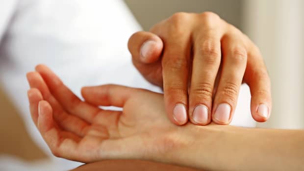 ein Arzt misst den Puls einer Patientin