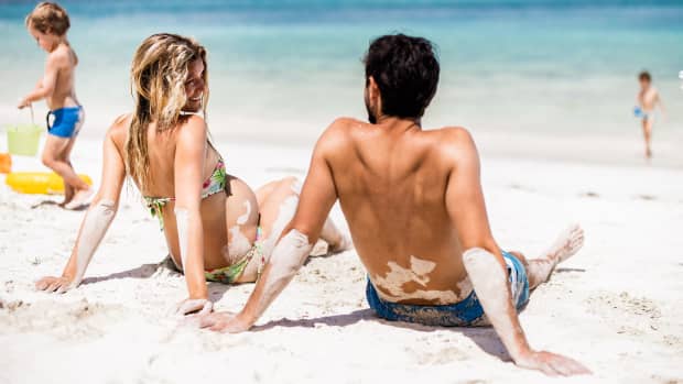 Eine schwangere Frau sitzt mit ihrem Partner am Strand