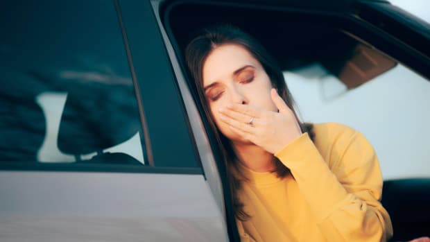Frau steigt aus dem Auto und leidet unter Reisekrankheit.