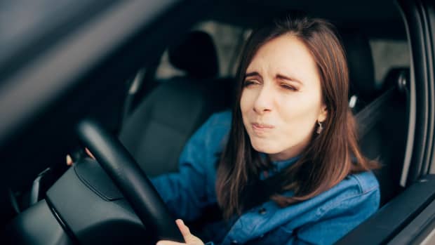 Eine junge Frau verzieht das Gesicht im Auto