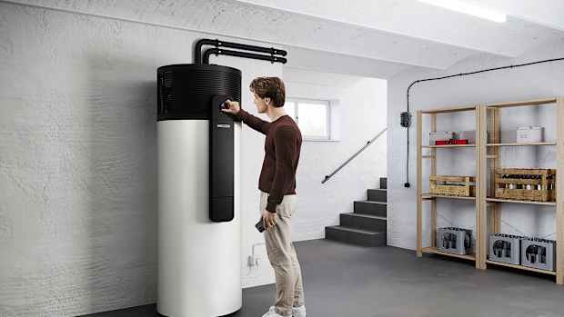 Aufnahme einer Brauchwasserwärmepumpe im Keller eines Wohnhauses der Markte Stiebel Eltron welche von einem Mann bedient wird