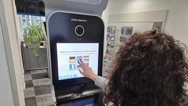Eine Frau die an einem Automaten Passbilder in digitaler form erstellt.