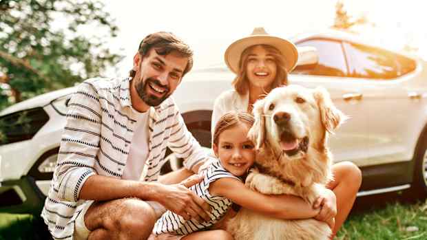 Eine Familie mit ihrem Labrador vor dem Auto