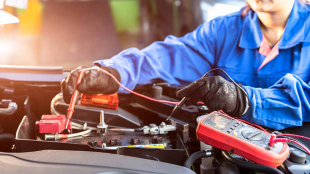 Techniker messen die Spannung der Batterie im Auto