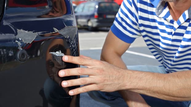 Mann zeigt auf Schaden an seinem Auto