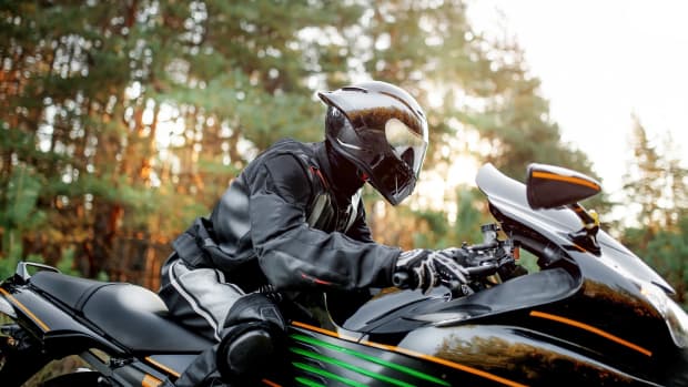 Ein Motorradfahrer in bester Schutzkleidung auf seiner Maschine im Wald