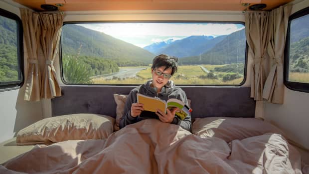 Ein junger Mann liest ein Buch in seinem Camper