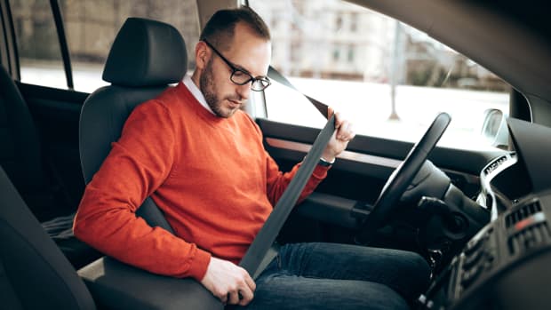 Mann schnallt sich im Auto an