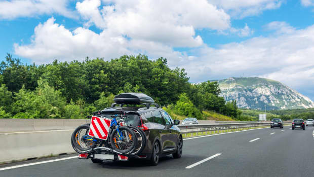 Auto mit Dachbox und Fahrrädern auf dem Fahrradträger auf der Autobahn