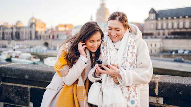 Zwei frauen schauen auf ein Mobiltelefon und lachen gemeinsam