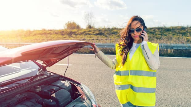 Eine Frau mit Warnweste hat eine Autopanne