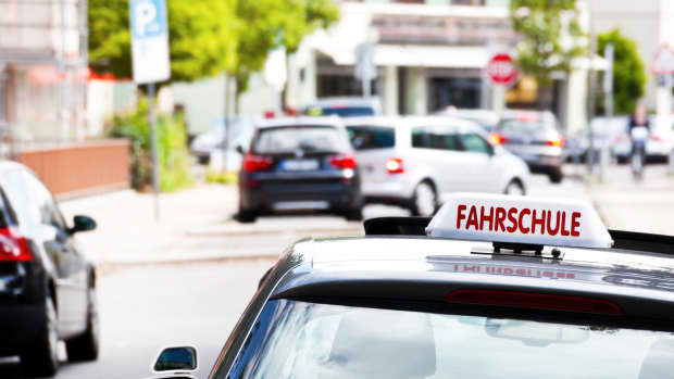 Ein Fahrschulauto ist von hinten auf einer Straße zu sehen