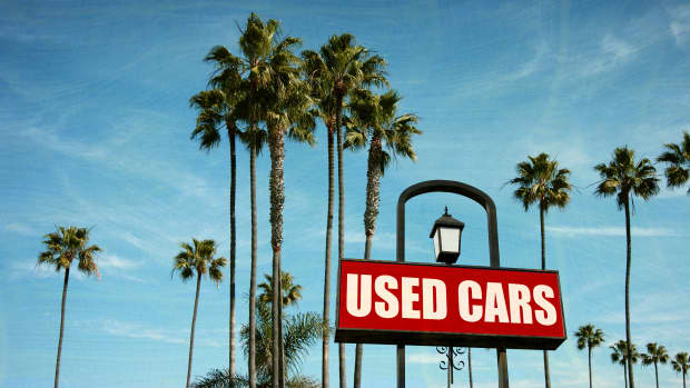 Ein Schild "Used Cars" unter Palmen