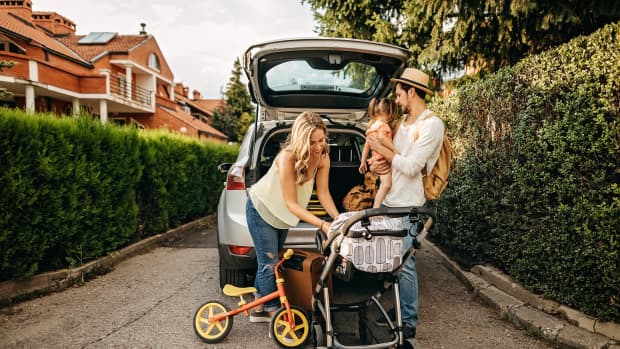 Aufnahme einer Familie mit Kinderwagen und Kind vor einem Kombi