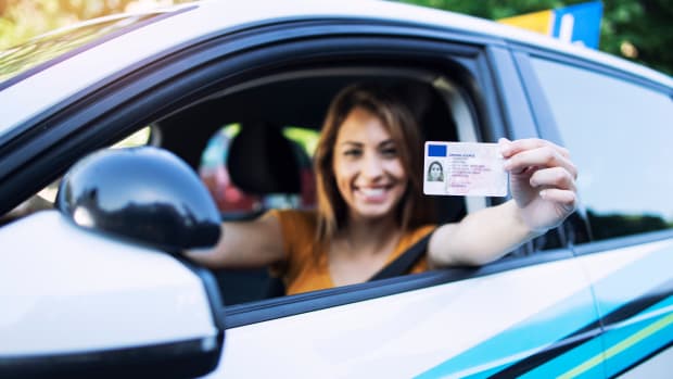 Eine junge Frau hält ihren Führerschein in die Kamera