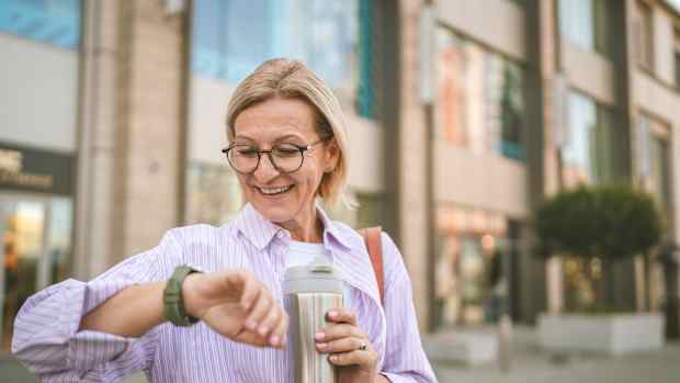 Eine Frau schaut hocherfreut auf Ihre Smartwatch