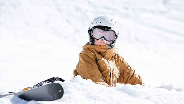Ein Junge liegt nach einem Sturz mit Ski im Schnee