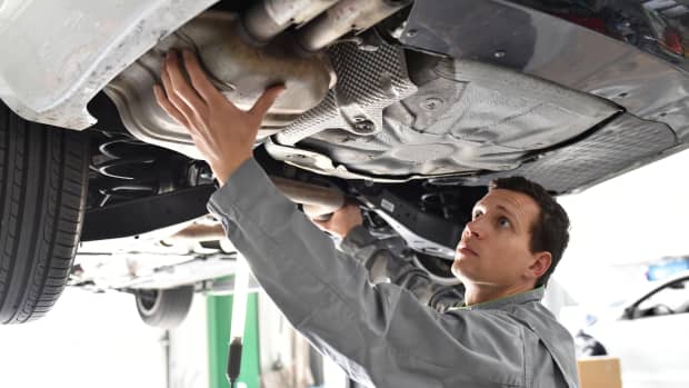 Automechaniker arbeitet am Katalysator