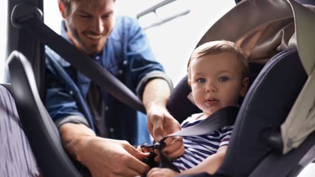 Mann schnallt sein Kind im Kindersitz an