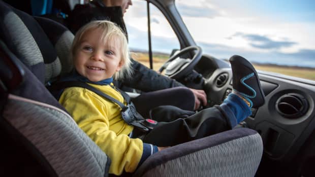 Ein Kind, das auf dem Vordersitz im Kindersitz auf einem großen Wohnmobil sitzt und glücklich lächelt