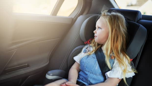 Mädchen sitzt angeschnallt im Kindersitz im Auto