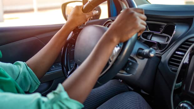 Frau sitzt im Auto und hält das Lenkrad fest
