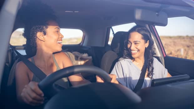 Zwei Frauen sitzen lachend im Auto