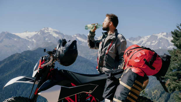 Ein Motorradfahrer macht Pause um etwas trinken