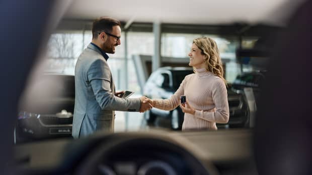 Ein Autoverkäufer schüttelt die Hand einer Kundin
