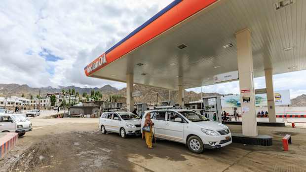 Autofahrer tanken an einer Tankstelle in Indien