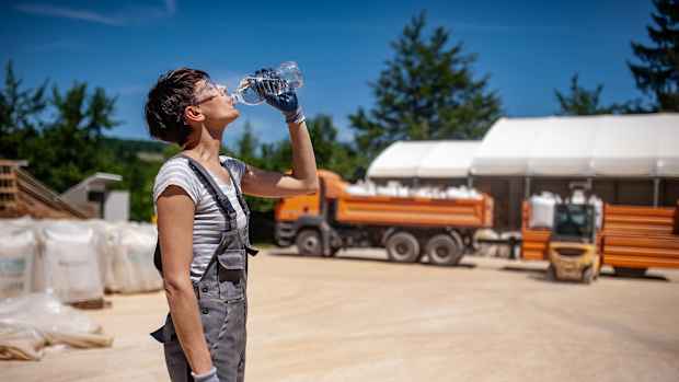 Eine Frau arbeitet in der Hitze und erfrischt sich mit Wasser