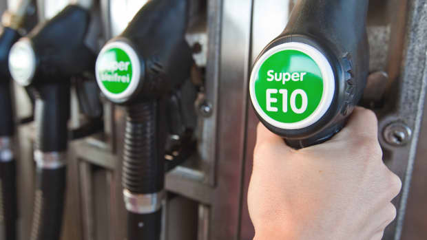 Hand greift nach Tankstutzen mit Super E10