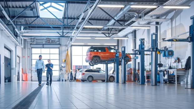 Zwei Personen laufen durch eine Autowerkstatt