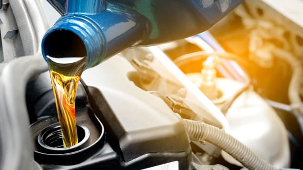 Öl lauft aus einem Kanister in einen Automotor