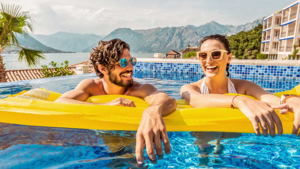 Ein Paar lehnt sich auf eine Luftmatratze im Hotelpool