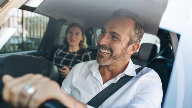 Ein Mann fährt Auto und lacht.